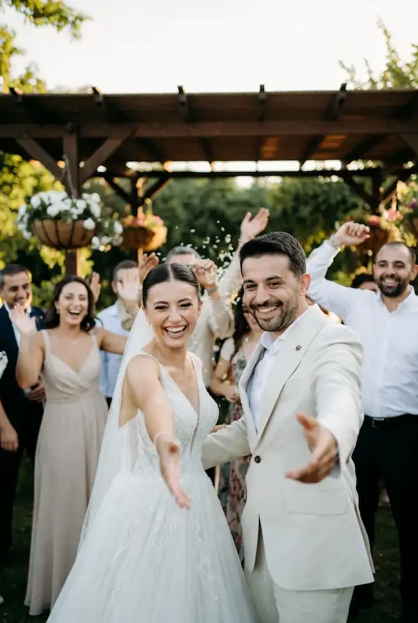 Mutlu gelin ve damat arkada misafirlerin fotoğraf çektiği düğün karesi